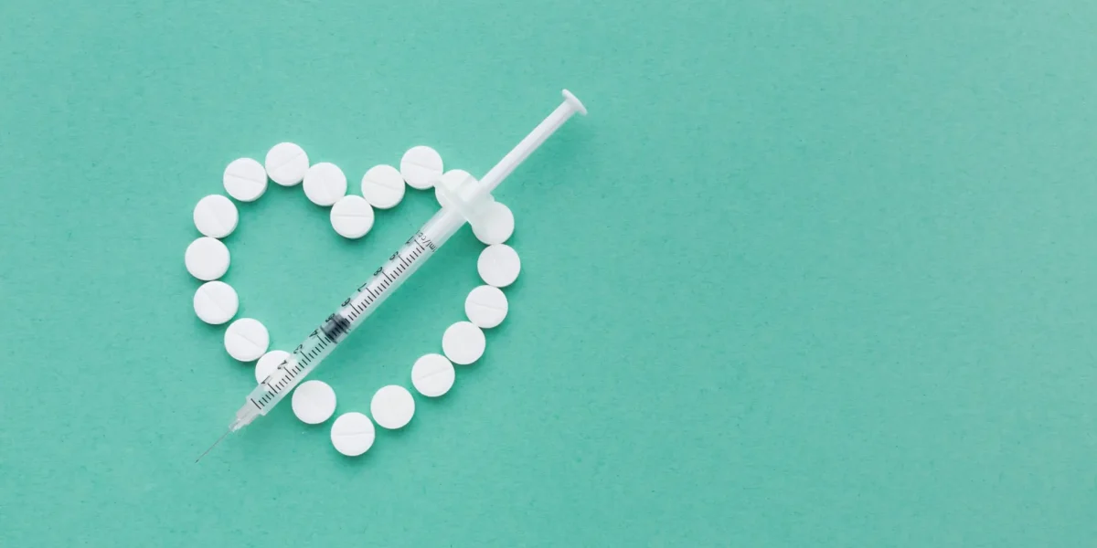 Abnehmspritze und ein aus Tabletten geformtes Herz