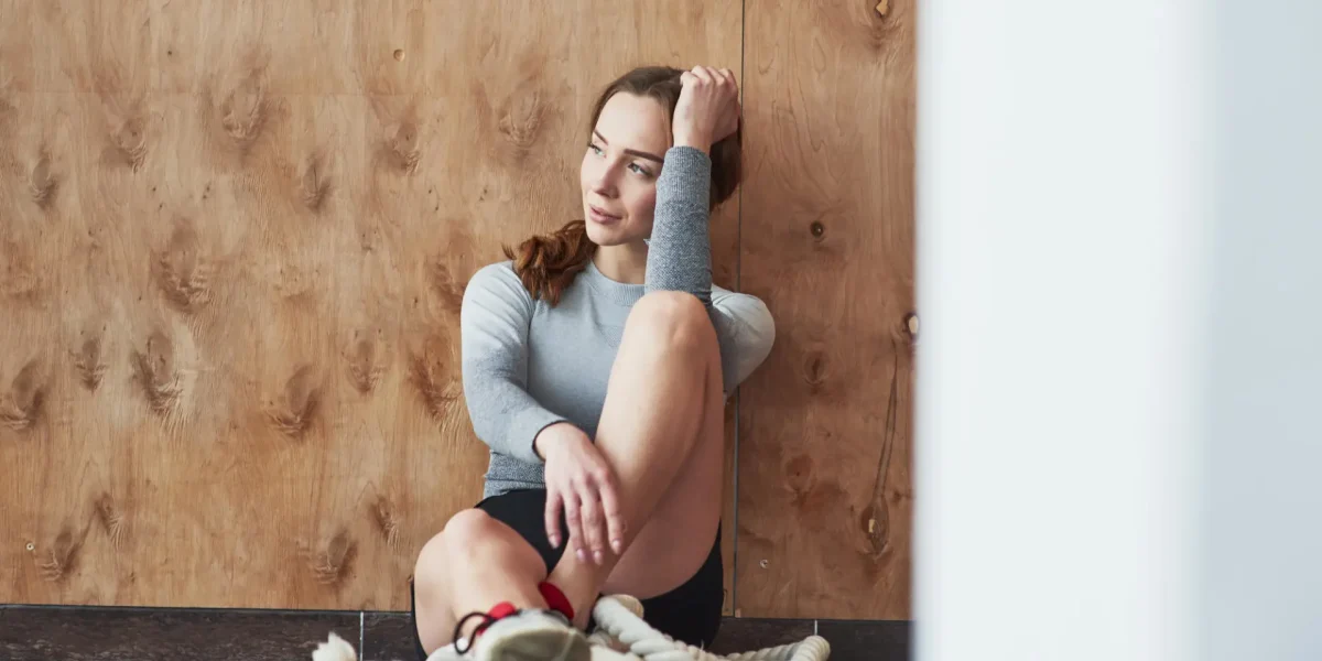 An die Holzwand gelehnt. Sportliche junge Frau beim Fitnesstag im Fitnessstudio