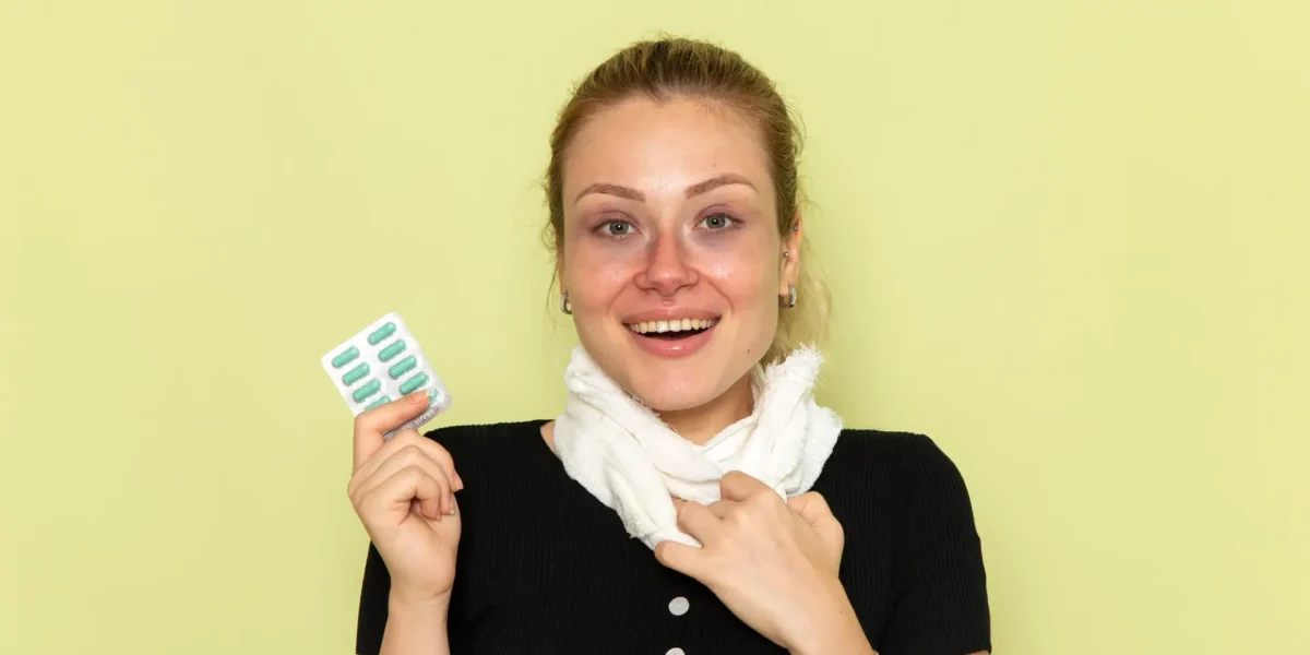 Frau mit Schal hält eine Medikamentenpackung und symbolisiert die Frage nach Antibiotika und der Wirkung der Pille.