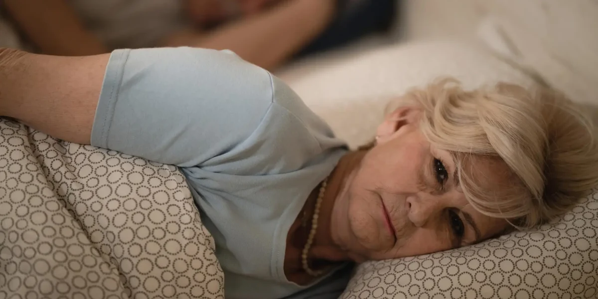 Ältere Frau liegt nachts wach im Bett