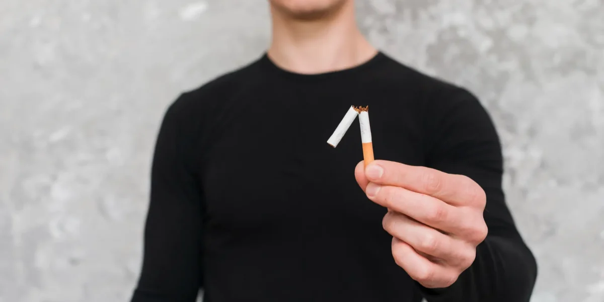 Mann hält zerbrochene Zigarette in der Hand
