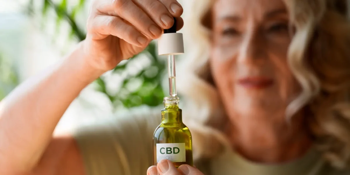 Frau hält eine Flasche CBD-Öl und zieht mit einer Pipette Öl daraus auf.