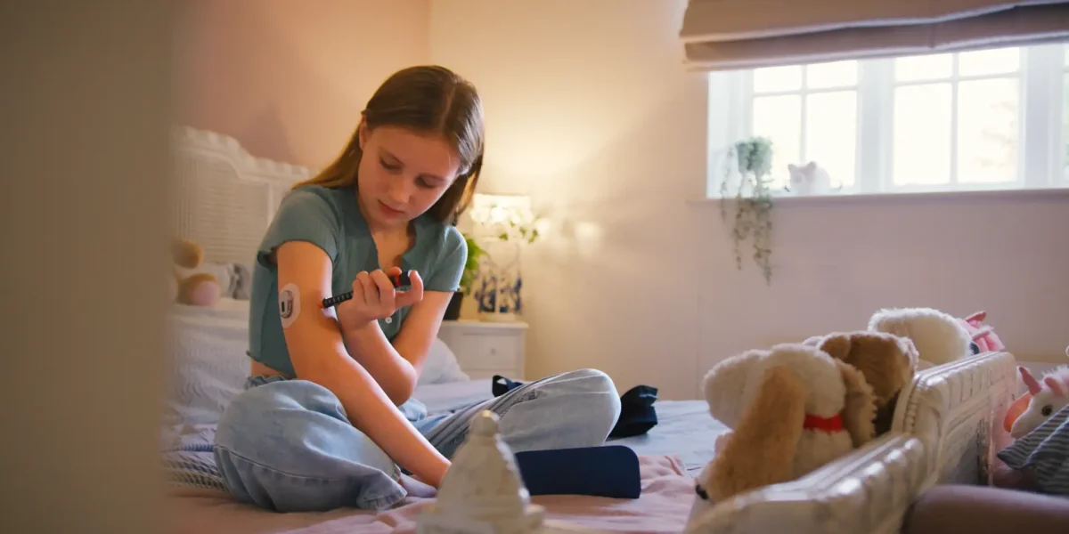Mädchen spritzt sich auf dem Bett sitzend Insulin