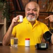 Senior lächelt mit Blutdrucktabletten in die Kamera