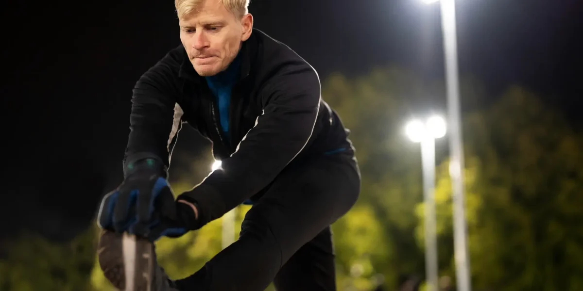 Mann stretcht abends vor dem Jogging