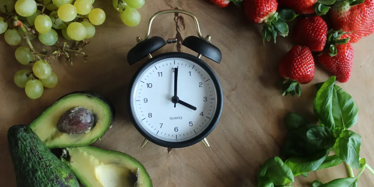 Wecker inmitten von Lebensmitteln als Symbol für Chrononutrition