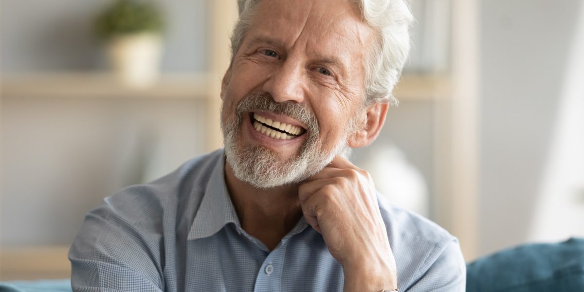 Älterer Mann, der lachend in die Kamera schaut