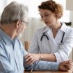 Junge Frau Doktorin mit weißer Uniform, mit Stethoskop zur Kontrolle des reifen Blutdrucks eines Patienten bei der Sitzung im Krankenhaus.