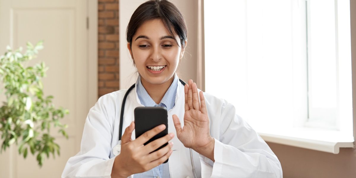 Junge Ärztin, die in ihr Handy schaut