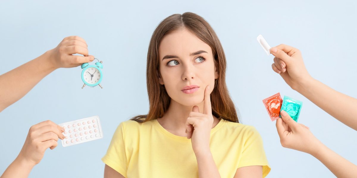 Junge Frau, die von allen Seiten Verhütungsmethoden gereicht bekommt