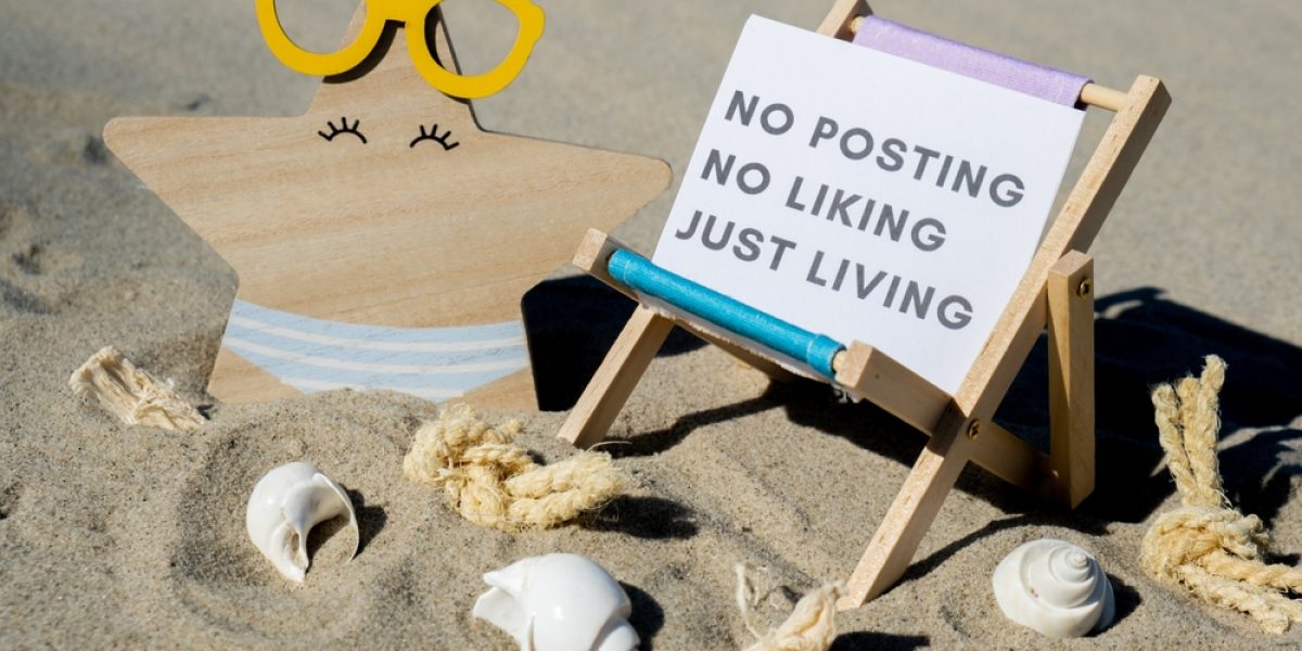 Plage avec coquillages et chaise longue portant un panneau "no posting no liking just living", illustrant une digital detox en vacances