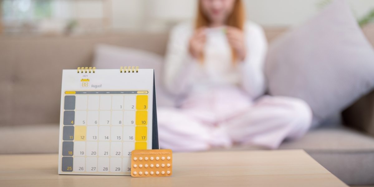 Pilules contraceptives avec calendrier sur une table, illustrant la gestion du cycle et le décalage des règles.