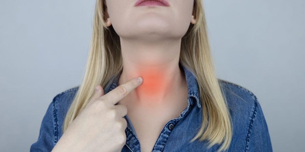 Femme montrant la zone de la thyroïde dans le cou, illustration d’un dérèglement thyroïdien en été