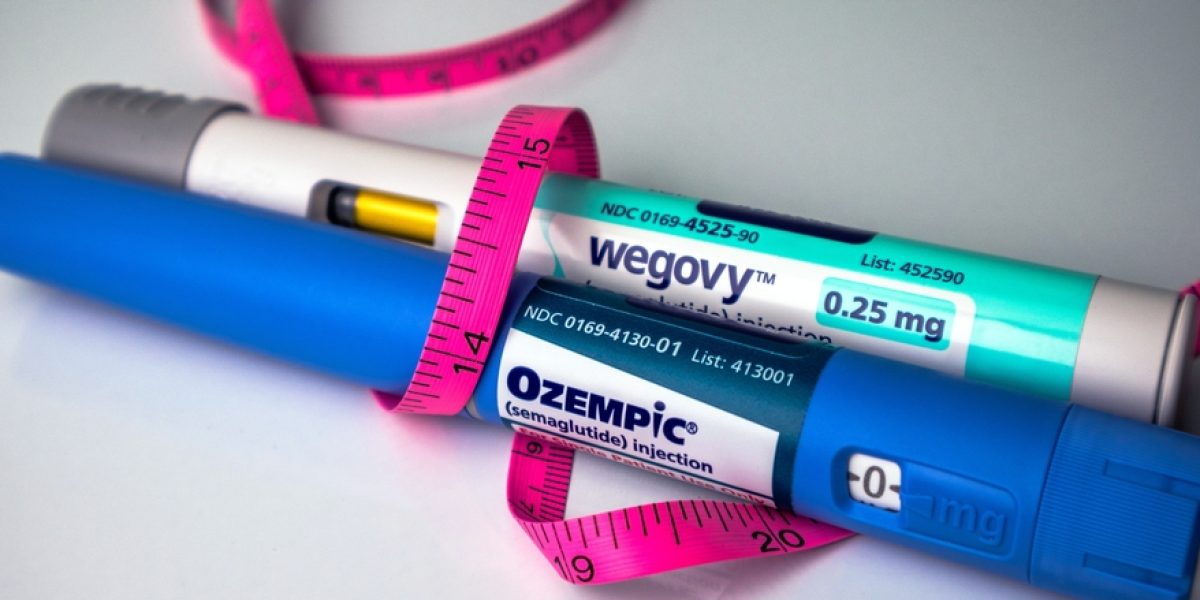 Stylos Ozempic et Wegovy posés sur une surface blanche avec un mètre-ruban, illustration d’un traitement GLP-1 pour la perte de poids.