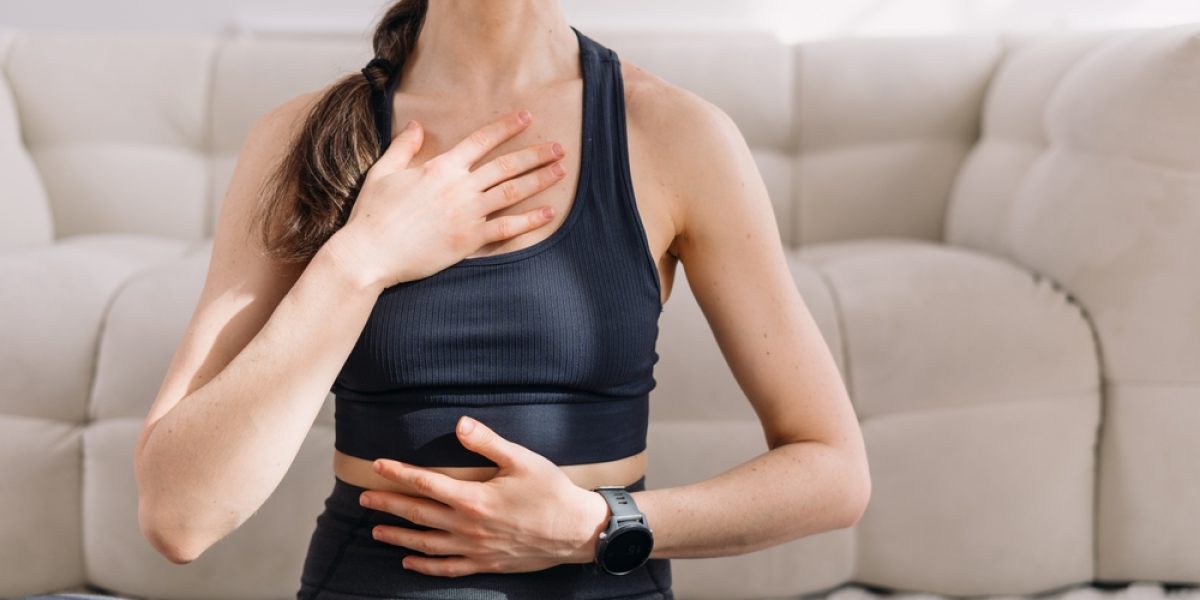 Femme pratiquant la méthode Buteyko dans son salon, en position de méditation